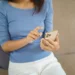 Mulher utilizando celular para acompanhar transferência automática de pensão alimentícia pelo Pix Pensão.