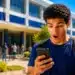 Estudante consulta resultado do Fies 2026 pelo celular em frente a uma universidade