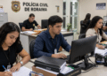 Estagiários trabalham em computadores e analisam documentos na Polícia Civil de Roraima.