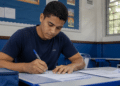 Jovem preenche formulário em sala de aula durante inscrição para processo seletivo.