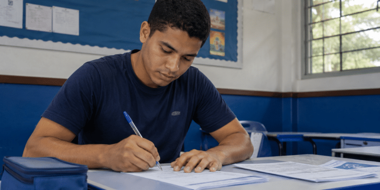 Jovem preenche formulário em sala de aula durante inscrição para processo seletivo.