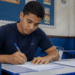 Jovem preenche formulário em sala de aula durante inscrição para processo seletivo.
