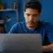 Jovem estudando pelo computador ao lado de um livro do Encceja, representando a dúvida sobre fazer a prova pela internet em 2026.
