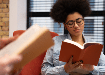 Jovem lê um livro em um ambiente de estudo, representando o ranking das obras mais procuradas no MEC Livros.