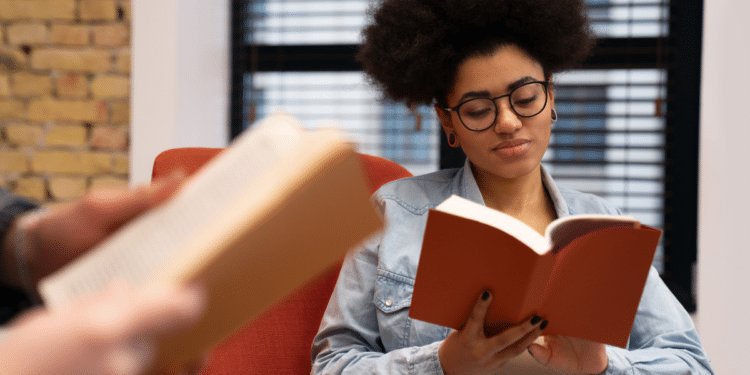 Jovem lê um livro em um ambiente de estudo, representando o ranking das obras mais procuradas no MEC Livros.