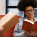 Jovem lê um livro em um ambiente de estudo, representando o ranking das obras mais procuradas no MEC Livros.