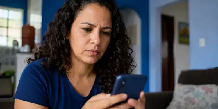 Mulher mexendo no celular, representando a tentativa de recuperar o acesso ao Facebook sem lembrar o e-mail e a senha.