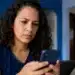 Mulher mexendo no celular, representando a tentativa de recuperar o acesso ao Facebook sem lembrar o e-mail e a senha.