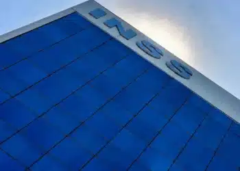 Fachada do prédio do INSS em vidro azul representando avanço na redução da fila de atendimento e aumento na concessão de benefícios