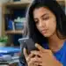 Jovem universitária consulta o celular em casa, representando a espera pelo resultado dos pré-selecionados do Fies 2026.2.