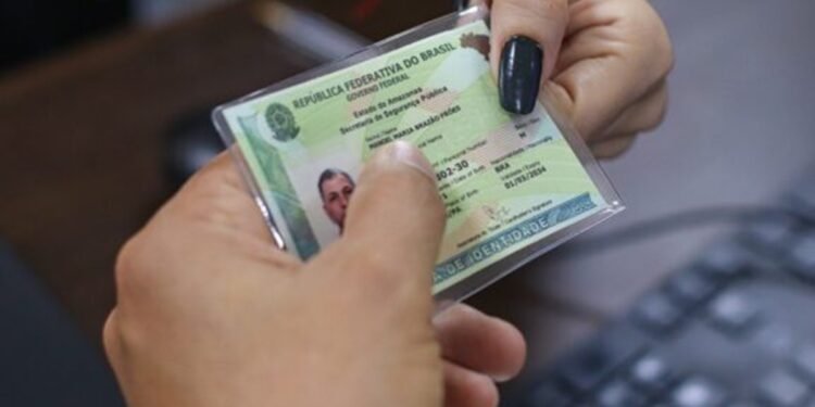 Pessoa segurando uma carteira de identidade no modelo antigo diante do rosto