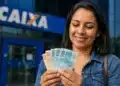 Mulher conta cédulas em frente a uma agência da Caixa, representando a liberação de mais de R$ 6 mil por meio do saque do FGTS.