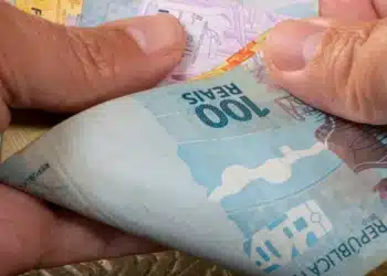 Mãos segurando cédulas de real representando o saque de R$ 6,2 mil do FGTS liberado para moradores afetados em São Paulo