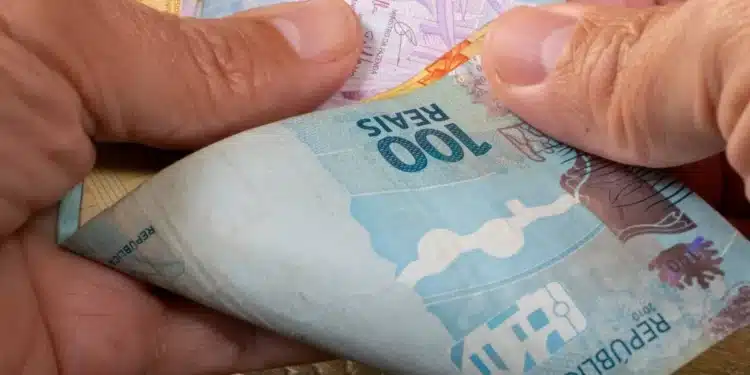 Mãos segurando cédulas de real representando o saque de R$ 6,2 mil do FGTS liberado para moradores afetados em São Paulo