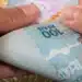 Mãos segurando cédulas de real representando o saque de R$ 6,2 mil do FGTS liberado para moradores afetados em São Paulo