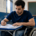 Estudante cadeirante realiza atividade escrita em sala de aula para o Enade 2026.