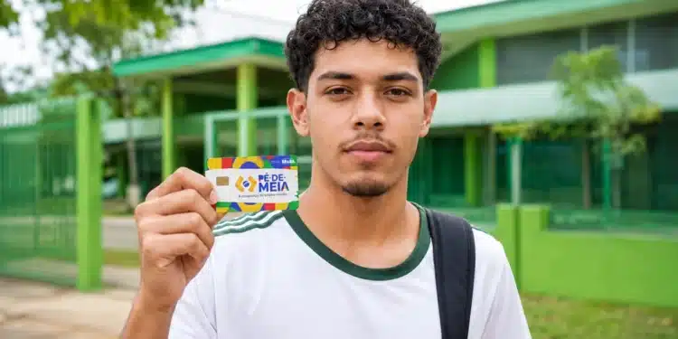 Jovem estudante brasileiro segurando o cartão do programa Pé-de-Meia em frente a uma escola pública.