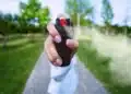 Mulher utilizando spray de pimenta em ambiente externo como símbolo de autodefesa após nova legislação sobre segurança feminina.