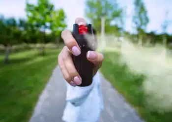 Mulher utilizando spray de pimenta em ambiente externo como símbolo de autodefesa após nova legislação sobre segurança feminina.