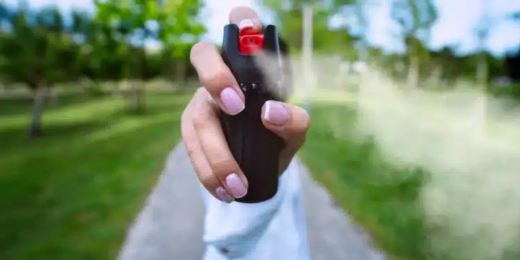 Mulher utilizando spray de pimenta em ambiente externo como símbolo de autodefesa após nova legislação sobre segurança feminina.