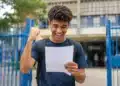 Estudante segurando documento de aprovação em frente a uma instituição de ensino, representando as vagas ofertadas pelo Fies 2026.2.