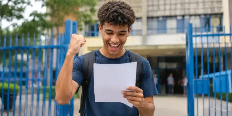 Estudante segurando documento de aprovação em frente a uma instituição de ensino, representando as vagas ofertadas pelo Fies 2026.2.