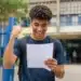 Estudante segurando documento de aprovação em frente a uma instituição de ensino, representando as vagas ofertadas pelo Fies 2026.2.