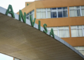 Letreiro verde ANVISA na entrada do prédio administrativo laranja com janelas em Brasília.