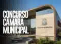 Fachada de Câmara Municipal com brasão visível, letras grandes “Concurso Câmara Municipal” e jardim na entrada.