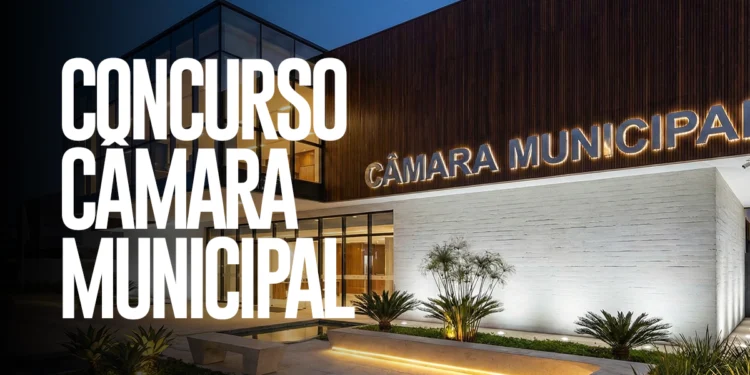 Fachada iluminada da Câmara Municipal com letreiro e anúncio de concurso público em destaque.