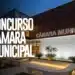 Fachada moderna da Câmara Municipal à noite com texto concurso em destaque e iluminação suave.