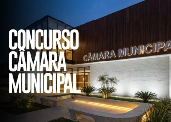 Fachada iluminada de Câmara Municipal com letreiro e anúncio de concurso público em destaque.