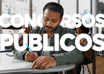 Homem jovem escrevendo em prova com letras grandes "Concursos Públicos" sobre a imagem.
