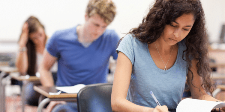 Estudantes concentrados realizando prova em sala de aula.
