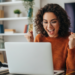 Jovem comemorando conquista ao computador ambiente doméstico alegre.