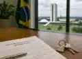 Contrato de locação residencial e chaves sobre mesa, com o Congresso Nacional ao fundo em Brasília.