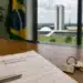 Contrato de locação residencial e chaves sobre mesa, com o Congresso Nacional ao fundo em Brasília.