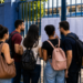 Candidatos consultam lista de aprovados em frente a uma escola após etapas do Concurso Nacional Unificado.