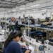 Trabalhadores em linha de produção durante expediente em fábrica de confecções, representando o avanço da PEC do fim da escala 6x1 para votação no Plenário.