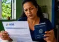 Mulher analisa documento do INSS segurando carteira de trabalho para entender regras de benefícios sem carência