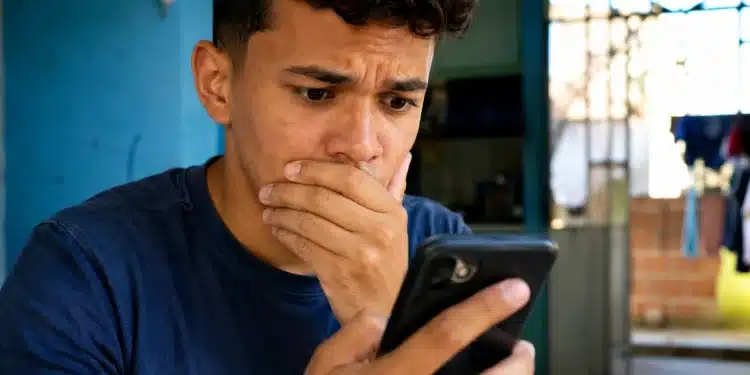 Jovem reage ao celular após bloqueio de acesso a plataformas de apostas