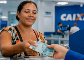 Beneficiária recebendo pagamento do Bolsa Família de agosto em agência da Caixa Econômica Federal.