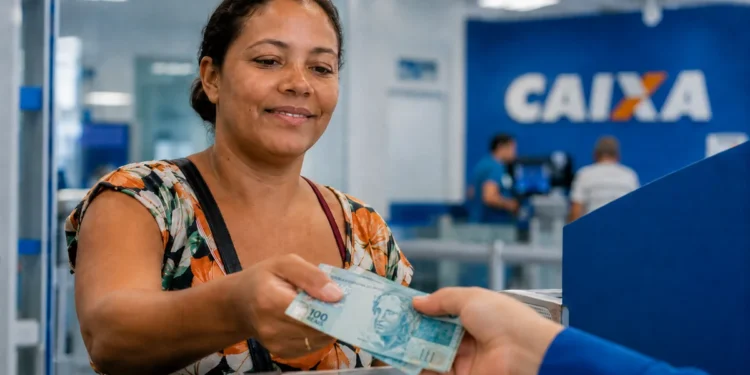 Beneficiária recebendo pagamento do Bolsa Família de agosto em agência da Caixa Econômica Federal.