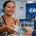Beneficiária recebendo pagamento do Bolsa Família de agosto em agência da Caixa Econômica Federal.