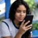 Estudante consulta informações do Pé-de-Meia pelo celular em ambiente escolar.