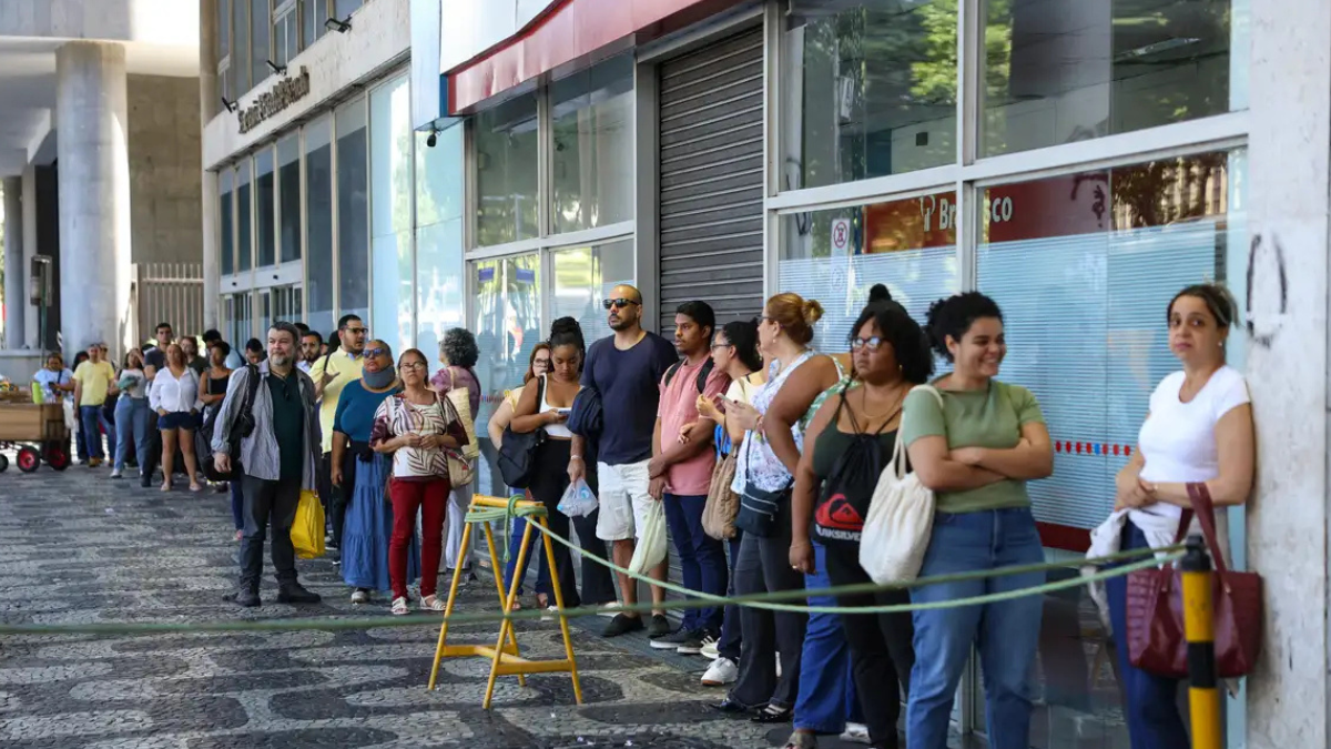 Pessoas aguardam em fila em frente a prédio público, em referência às vagas da 2ª edição do CNU.