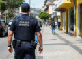 Guarda municipal fardado patrulha rua de cidade durante ação de segurança pública.
