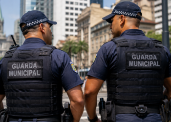 Dois guardas municipais de costas conversam em uma área urbana, representando a expectativa por novo concurso da Guarda Municipal de Natal-RN.