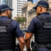 Dois guardas municipais de costas conversam em uma área urbana, representando a expectativa por novo concurso da Guarda Municipal de Natal-RN.