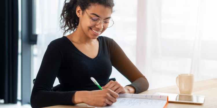 Pessoa estudando para concurso público com material de preparação sobre a mesa.